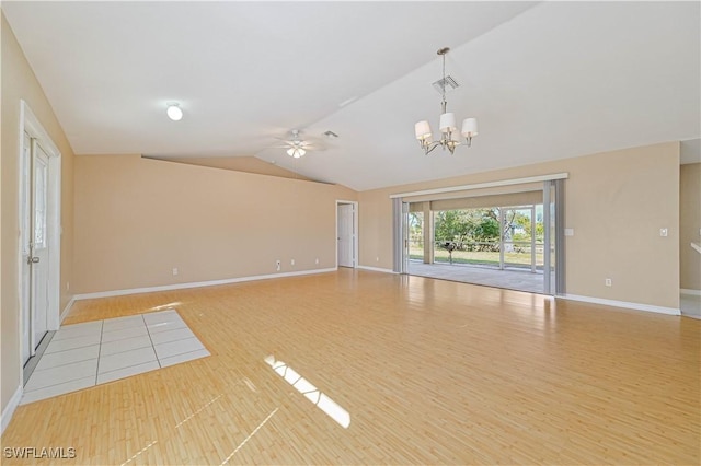 empty room featuring lofted ceiling, ceiling fan with notable chandelier, and light hardwood / wood-style flooring