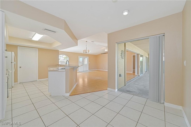 kitchen with light tile patterned flooring, white refrigerator, decorative light fixtures, and a chandelier