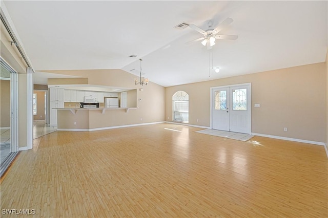 unfurnished living room with lofted ceiling, ceiling fan with notable chandelier, light hardwood / wood-style floors, and french doors