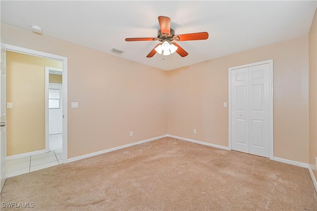 empty room with ceiling fan and light carpet