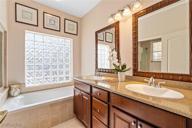 bathroom featuring vanity, tile patterned flooring, and a relaxing tiled tub