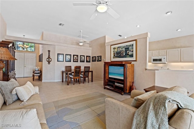 tiled living room with ceiling fan with notable chandelier