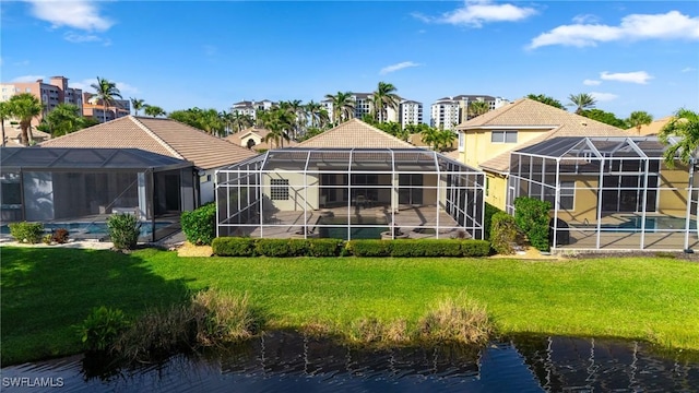 back of house with a yard, a lanai, and a water view