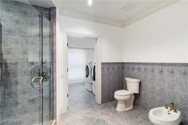 bathroom with tile walls, an enclosed shower, independent washer and dryer, a bidet, and tile patterned floors