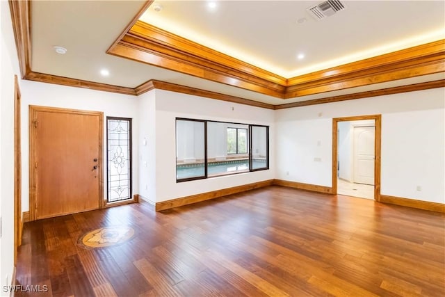 entryway with dark wood-type flooring, crown molding, and a raised ceiling