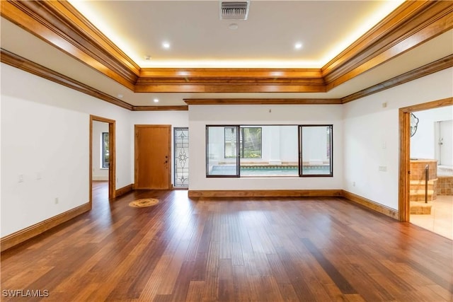 unfurnished room with a tray ceiling, dark wood-type flooring, and ornamental molding