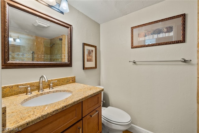 bathroom with toilet, tiled shower, and vanity