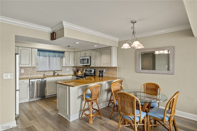 kitchen with kitchen peninsula, appliances with stainless steel finishes, decorative backsplash, light wood-type flooring, and sink