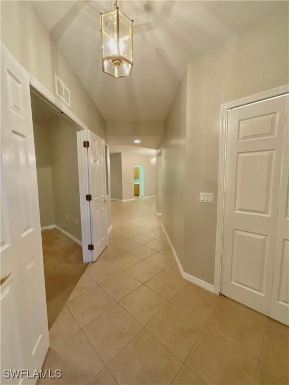 hall featuring light tile patterned floors and a notable chandelier