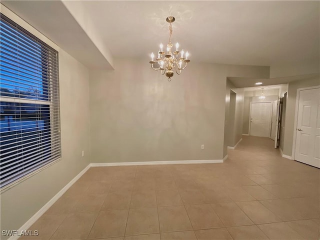 unfurnished room with an inviting chandelier and light tile patterned floors