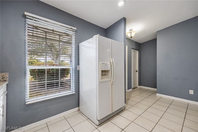 kitchen featuring white fridge with ice dispenser, white cabinetry, and light tile patterned floors