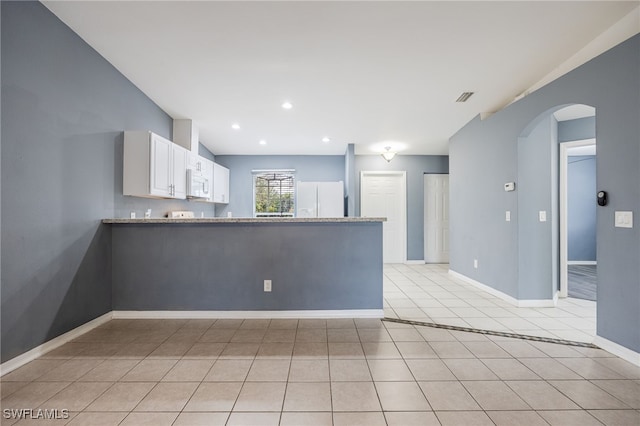 kitchen featuring white appliances, white cabinets, kitchen peninsula, light stone counters, and light tile patterned floors