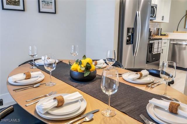 kitchen with hardwood / wood-style floors, stainless steel appliances, decorative backsplash, and white cabinetry