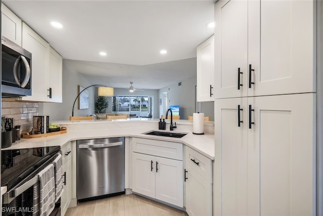 kitchen with appliances with stainless steel finishes, white cabinetry, sink, backsplash, and ceiling fan