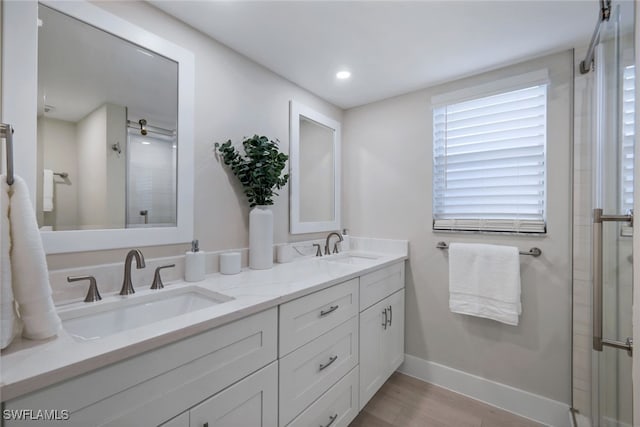 bathroom featuring a shower with shower door and vanity