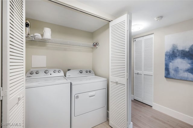 laundry area with independent washer and dryer and light hardwood / wood-style flooring