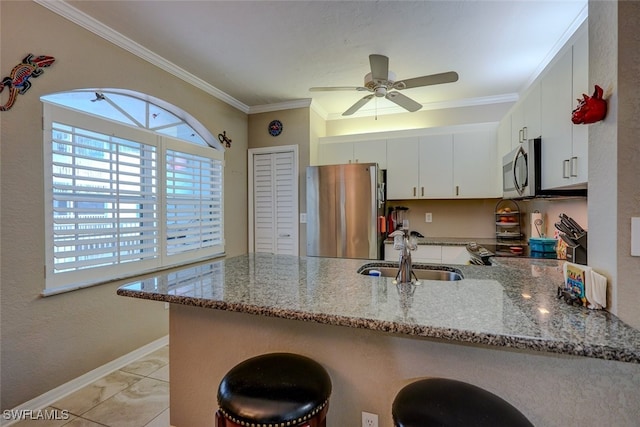 kitchen with sink, stainless steel appliances, kitchen peninsula, and white cabinets