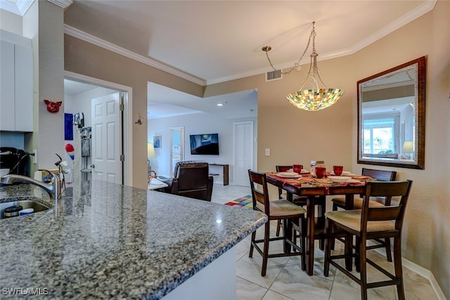 dining area featuring ornamental molding, sink, and light tile patterned flooring