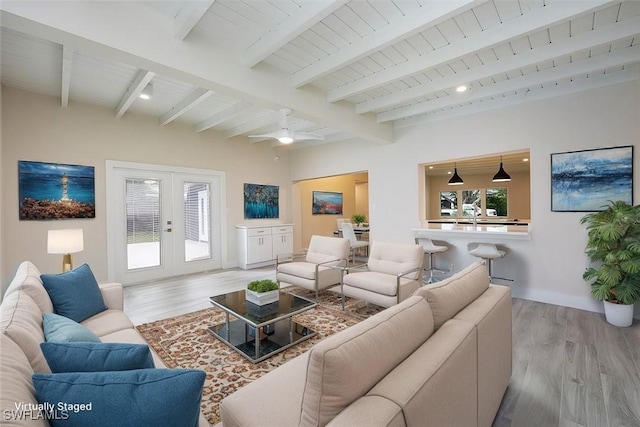 living area with french doors, beamed ceiling, and wood finished floors