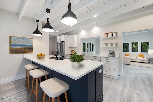 kitchen with black electric stovetop, a breakfast bar area, white cabinets, light countertops, and stainless steel fridge with ice dispenser