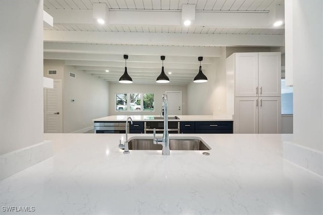 kitchen with visible vents, a sink, hanging light fixtures, and beamed ceiling