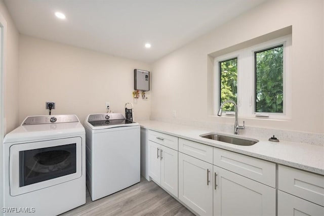 laundry room with light wood finished floors, washing machine and clothes dryer, a sink, and recessed lighting