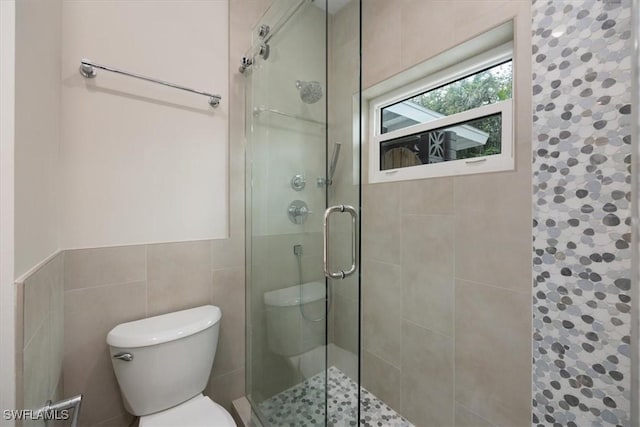 full bathroom featuring toilet, a stall shower, and tile walls