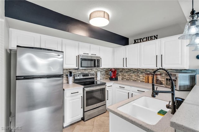 kitchen featuring decorative light fixtures, sink, white cabinetry, and stainless steel appliances