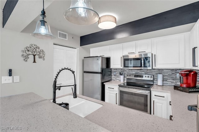 kitchen with stainless steel appliances, white cabinets, tasteful backsplash, and sink