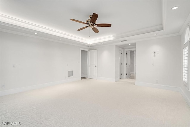 carpeted spare room featuring ceiling fan, a tray ceiling, and ornamental molding