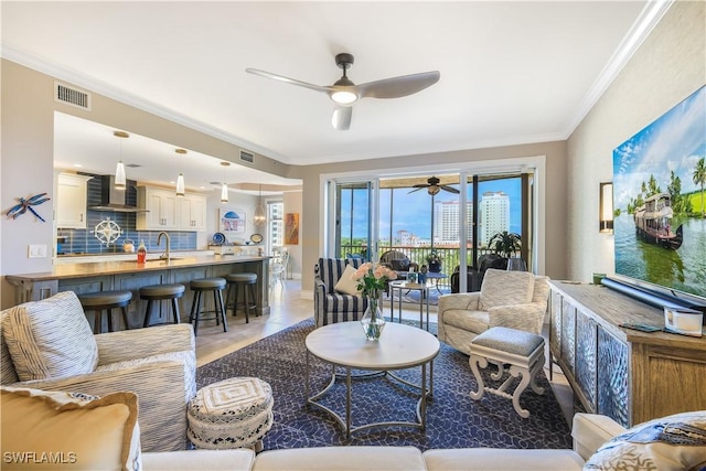 tiled living room with ceiling fan, ornamental molding, and sink