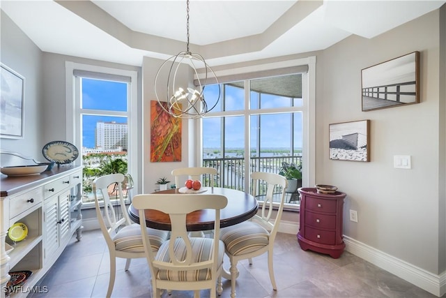 dining space with a tray ceiling and a chandelier