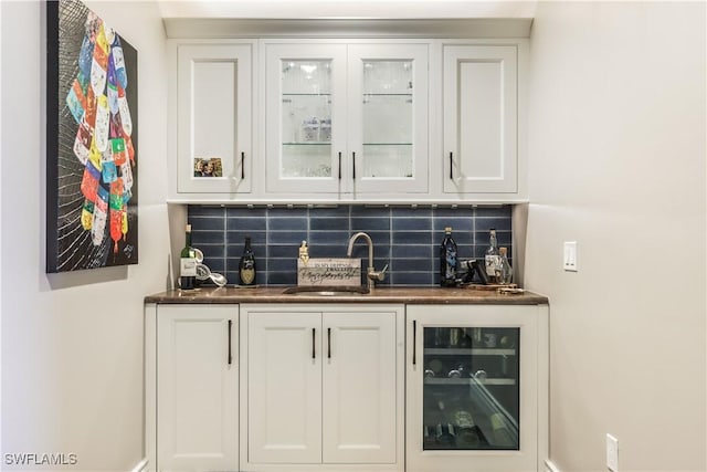 bar with white cabinets, backsplash, beverage cooler, and sink