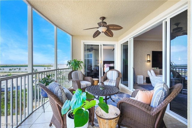 sunroom featuring ceiling fan and a water view