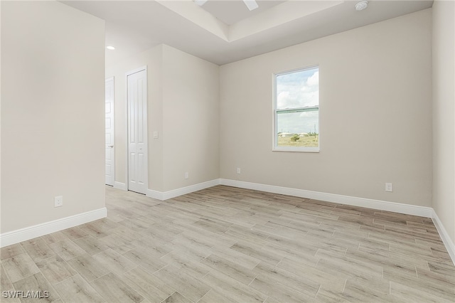 empty room featuring a raised ceiling and light hardwood / wood-style flooring