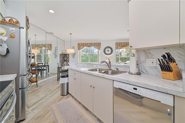 kitchen with appliances with stainless steel finishes, tasteful backsplash, pendant lighting, white cabinets, and sink