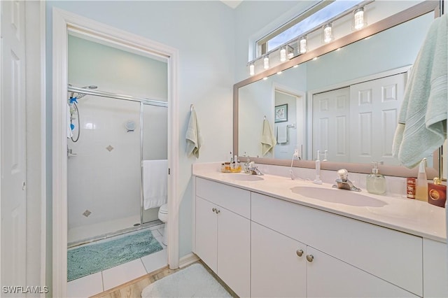 bathroom featuring a shower with shower door, vanity, tile patterned flooring, and toilet