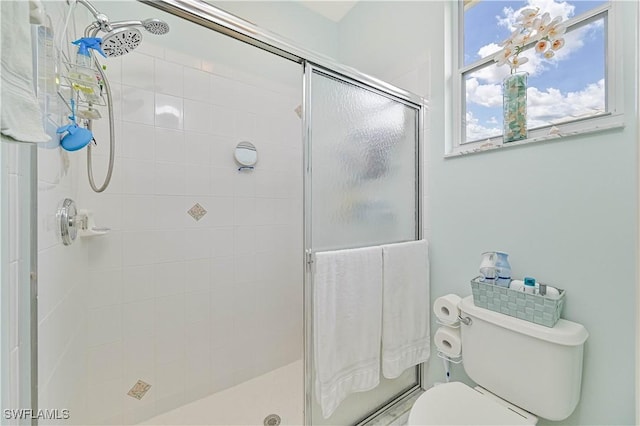 bathroom with a shower with shower door and toilet