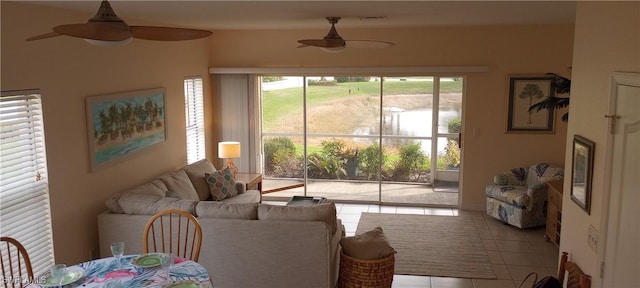 living room with a wealth of natural light, light tile patterned flooring, and ceiling fan