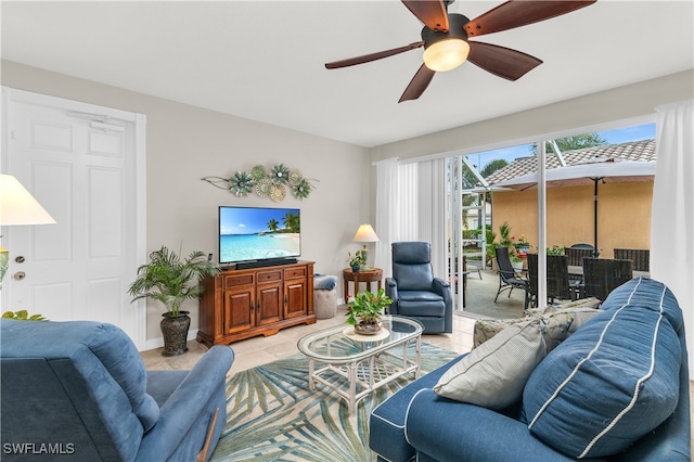 living area featuring baseboards, a ceiling fan, and tile patterned floors