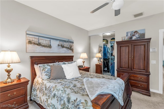 bedroom with a walk in closet, a closet, light colored carpet, visible vents, and a ceiling fan