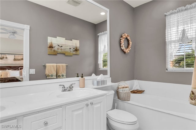 ensuite bathroom featuring double vanity, a healthy amount of sunlight, a sink, and a bath