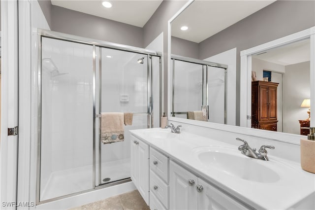 full bathroom featuring double vanity, a stall shower, tile patterned flooring, and a sink