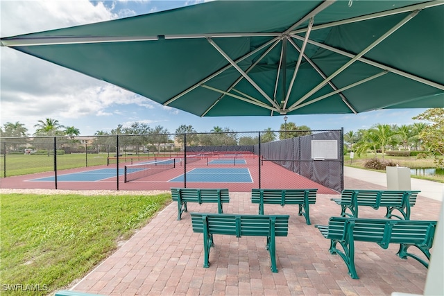 view of home's community with a yard, a tennis court, and fence