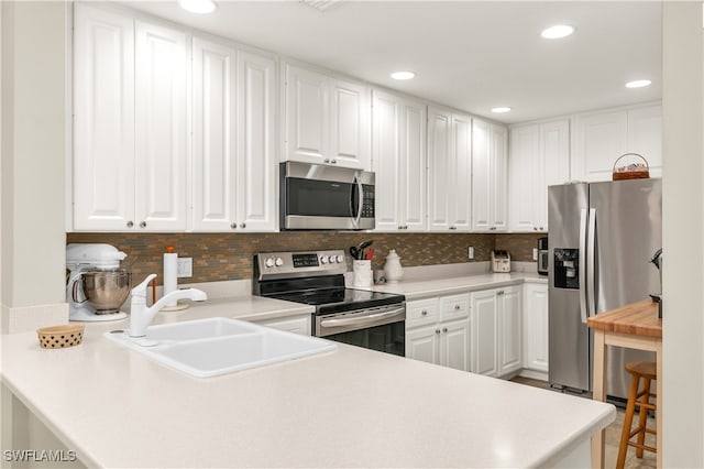 kitchen featuring stainless steel appliances, light countertops, white cabinetry, and a sink