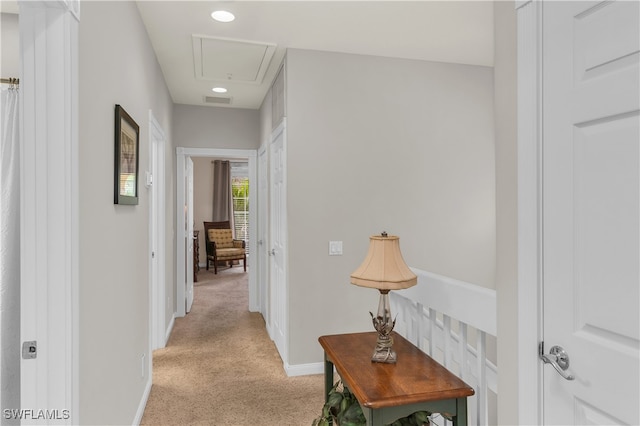 hallway with light carpet, attic access, visible vents, and baseboards