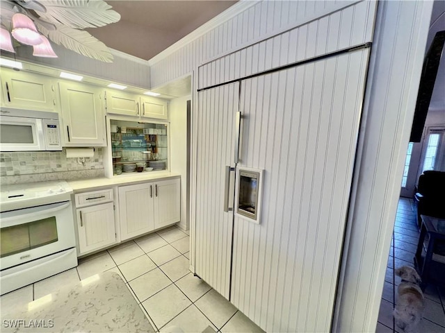 kitchen with light tile patterned flooring, tasteful backsplash, white cabinetry, ornamental molding, and white appliances