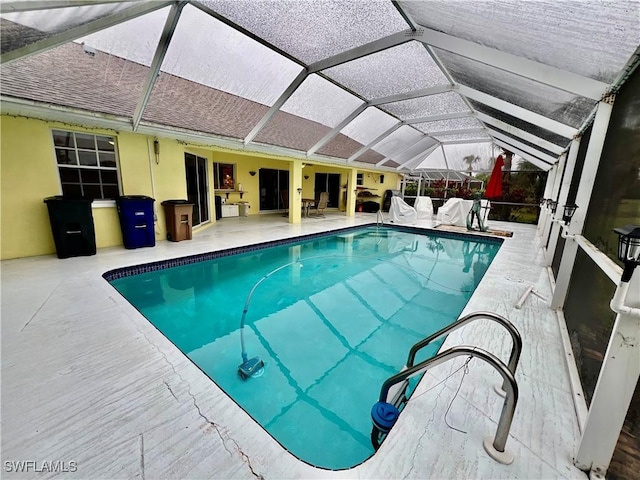 view of pool featuring glass enclosure and a patio area