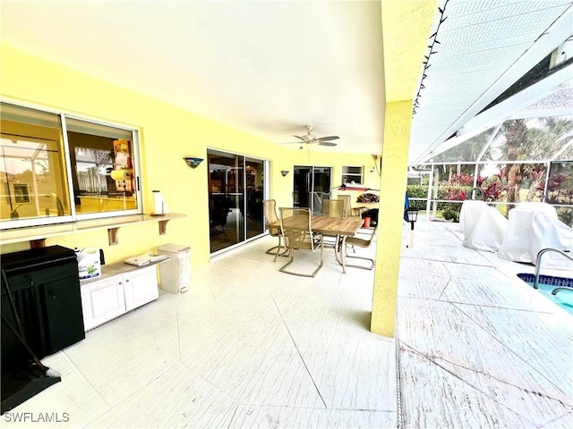 view of patio with ceiling fan, glass enclosure, and area for grilling