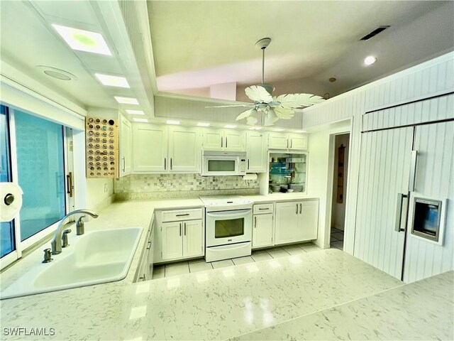 kitchen with white appliances, white cabinetry, sink, decorative light fixtures, and backsplash